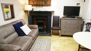 A living room with a brown sofa, a patterned rug, a fireplace, a television, and a wooden cabinet. - Perfect! for doing Galway City - sleeps 2+, walk everywhere... (Devon Place The Crescent Galway City)
