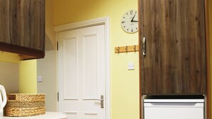 A kitchen with wooden cabinets, a white dishwasher, a white refrigerator, a clock on the wall, and a basket on the counter. - Perfect! for doing Galway City - sleeps 2+, walk everywhere... (Devon Place The Crescent Galway City)