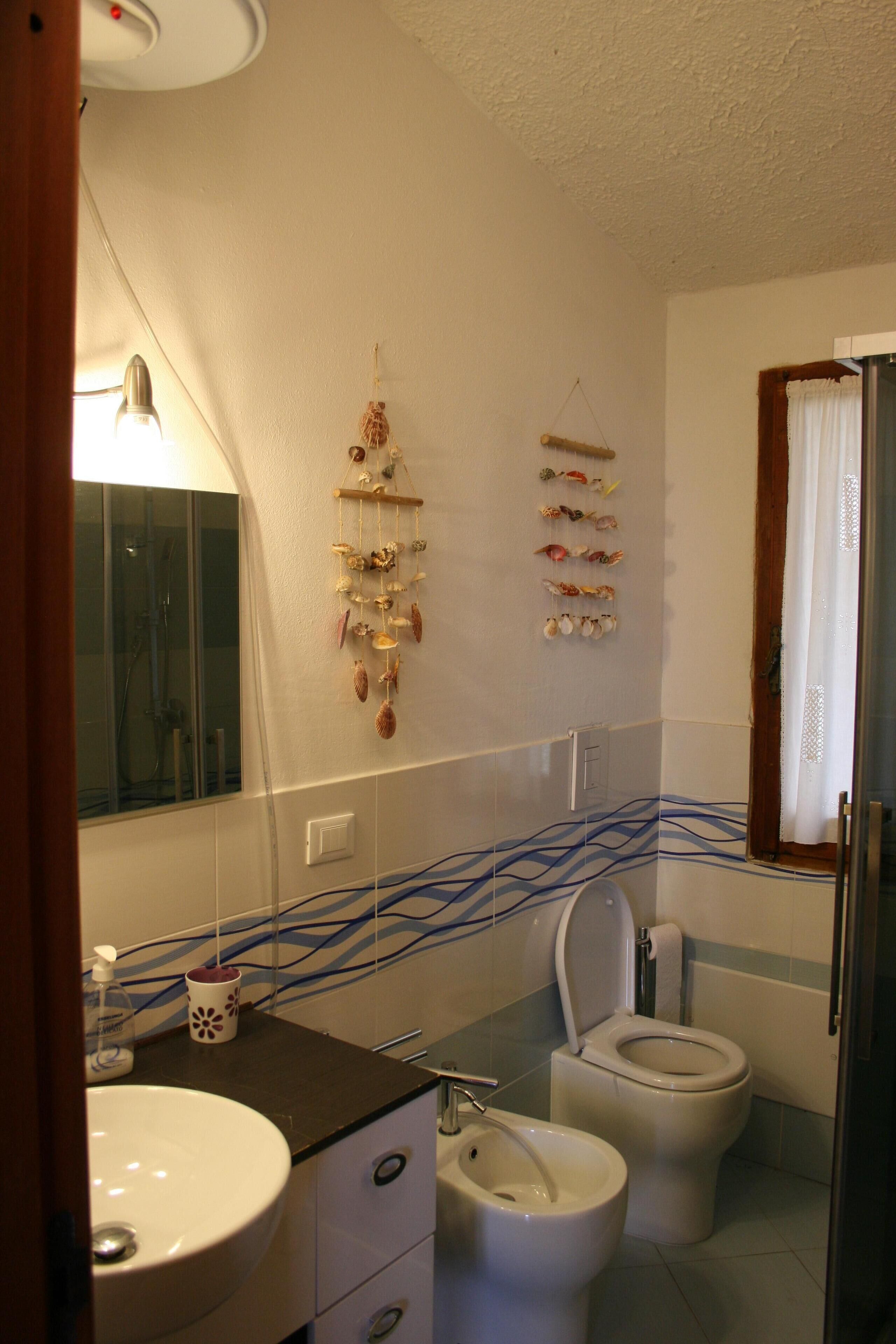 Une salle de bain équipée d’un lavabo, de deux toilettes, d’un miroir et d’une décoration murale.