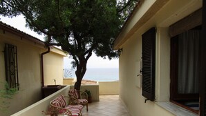 A balcony with wicker furniture, a potted plant, and a view of the sea. - House / Villa - independent  with beautiful sight on the gulf (Costa Rei)
