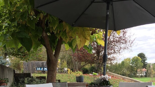 An outdoor patio area with a table and chairs, a large umbrella, and a garden with a wooden fence and a sign that reads "HAN". - Cottage in the countryside, less than 10 minutes from Mulhouse center, near Switzerland (Steinbrunn-Le-Bas)