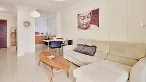 A modern living room with a sofa, coffee table, and a dining area with a table and chairs.