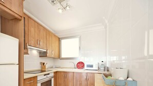 A kitchen with wooden cabinets, a white refrigerator, a microwave, and a sink.