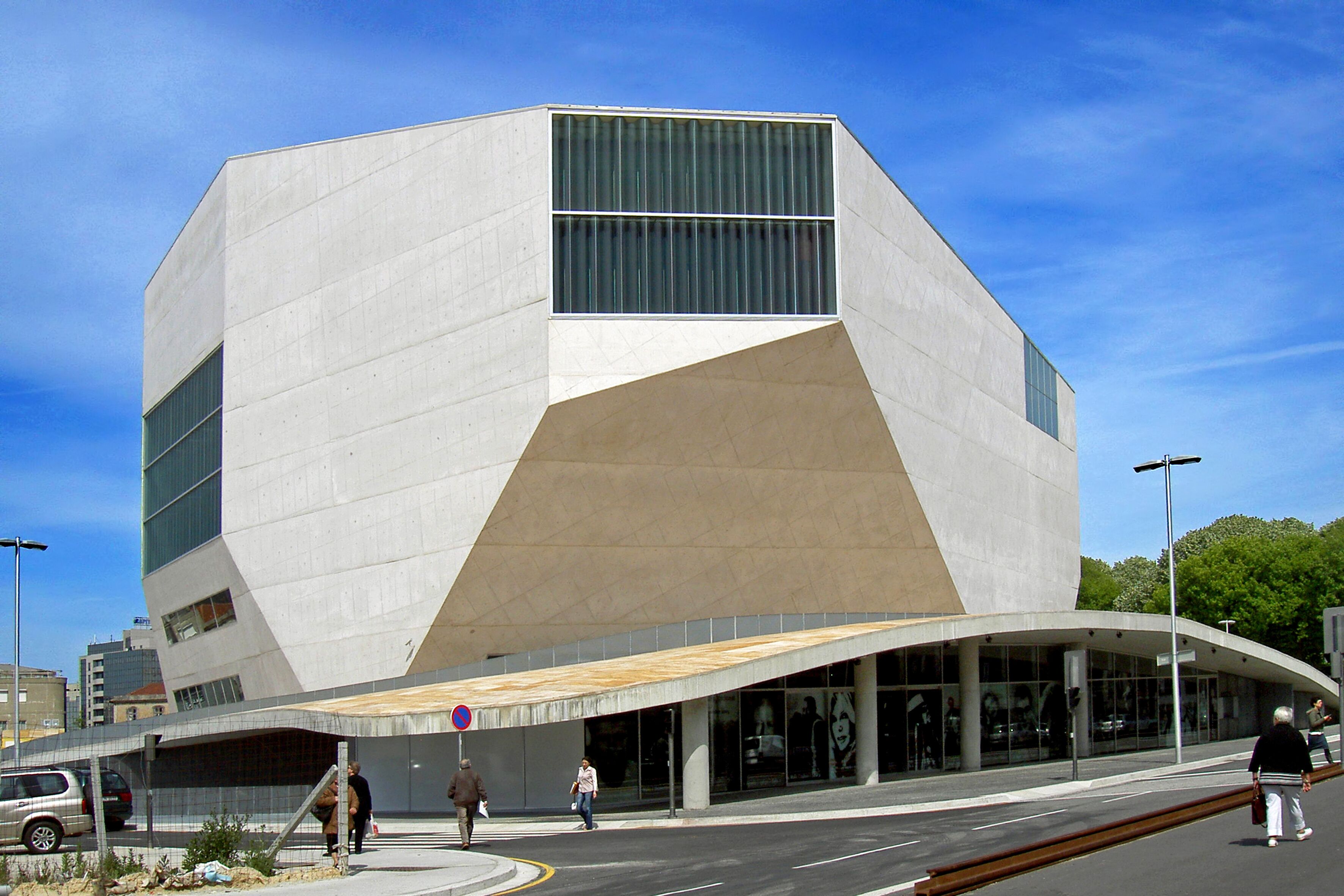 Ein modernes Gebäude mit einem markanten, eckigen Design, großen Fenstern und einem geschwungenen Eingang.