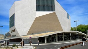 Ein modernes Gebäude mit einem markanten, eckigen Design, großen Fenstern und einem geschwungenen Eingang.