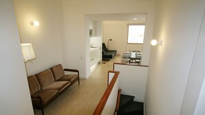 Ein modernes Wohnzimmer mit einem braunen Sofa, einem Essbereich mit Tisch und Stühlen sowie einer Treppe zu einer weiteren Ebene.