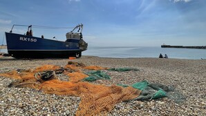 A boat named RX150 on a pebbled beach with fishing nets and a calm sea in the background. - Stunning  country Cottage in Westfield, East Sussex. (Westfield)