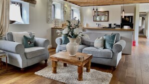 A modern living room with grey sofas, a wooden coffee table, and a white rug. - Stunning  country Cottage in Westfield, East Sussex. (Westfield)