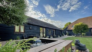 A modern wooden building with a garden area, including a pond and seating. - Stunning  country Cottage in Westfield, East Sussex. (Westfield)