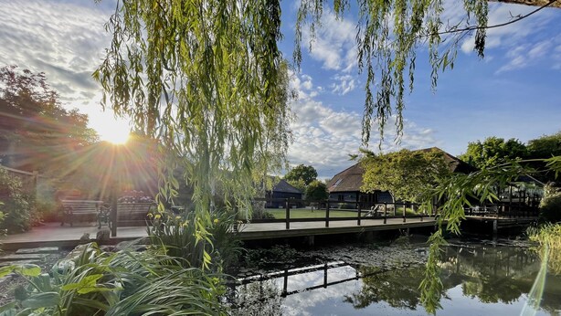 A serene riverside scene with a wooden bridge, a bench, and a gazebo under willow trees. - Stunning  country Cottage in Westfield, East Sussex. (Westfield)