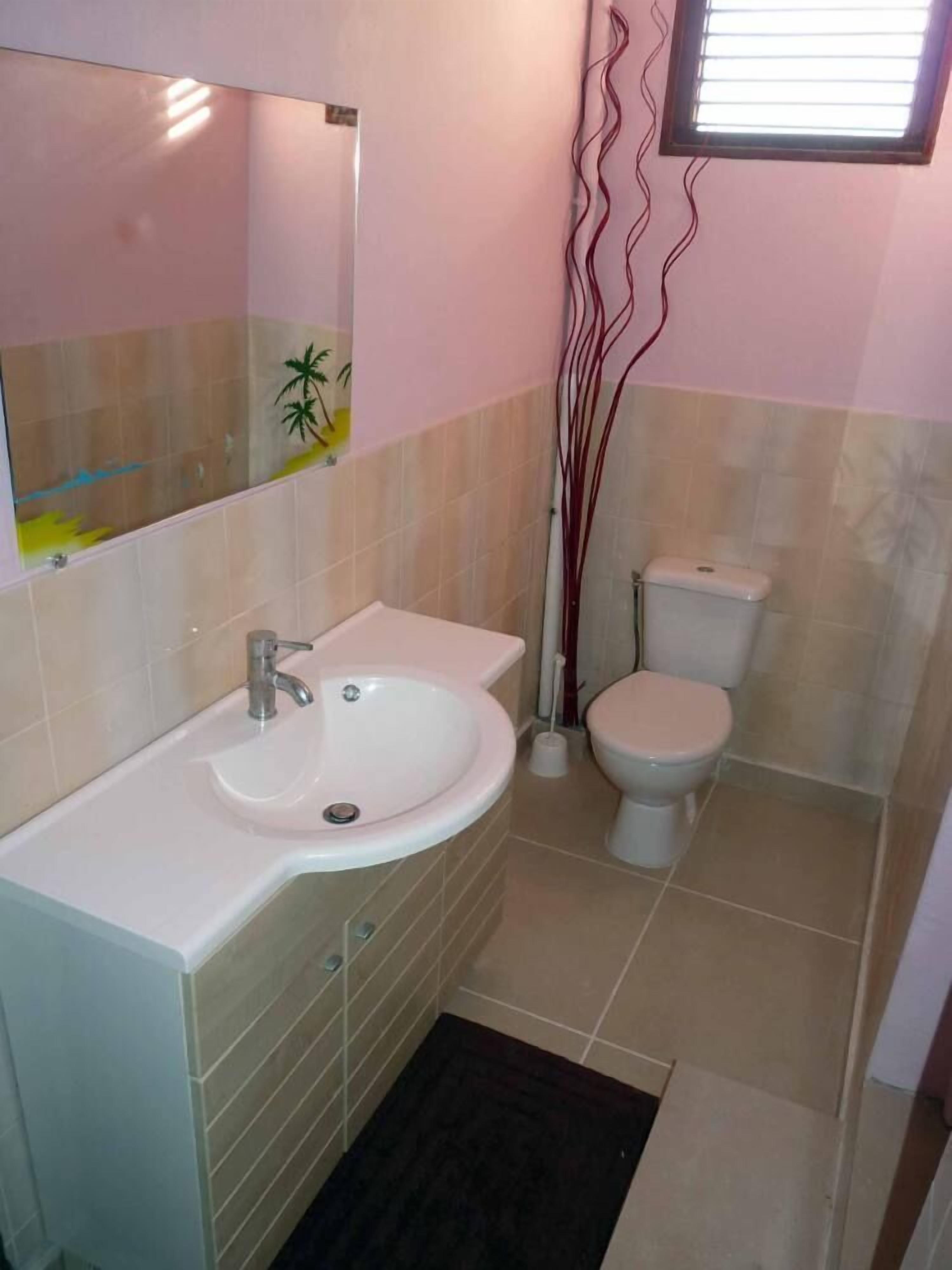 A bathroom with a white sink, mirror, and toilet.