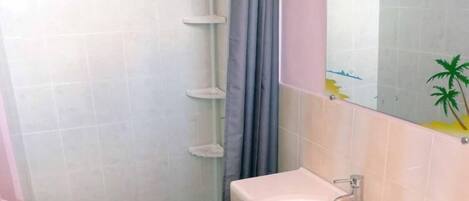 Ein Badezimmer mit weißem Waschbecken, einem Spiegel und einer Duschkabine.