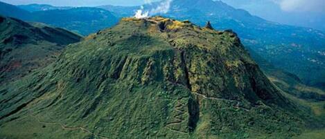 A volcanic landscape with a prominent peak and a visible trail.