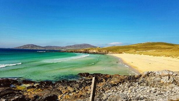 A coastal landscape with a sandy beach, rocky shoreline, and distant hills. - This is the stunning view of the Northern Lights (Aurora (Isle of Harris)