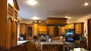 A spacious kitchen with wooden cabinetry, a central island, and a tiled backsplash. - This is the stunning view of the Northern Lights (Aurora (Isle of Harris)