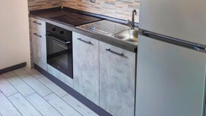 A modern kitchen with grey cabinets, a stainless steel sink, and a built-in oven.