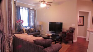 Un salon comprenant un canapé, un fauteuil, une table basse, un téléviseur et un ventilateur de plafond.