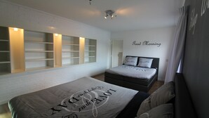 A bedroom with a bed, a nightstand, a wall-mounted shelf unit, and a 'Good Morning' sign.