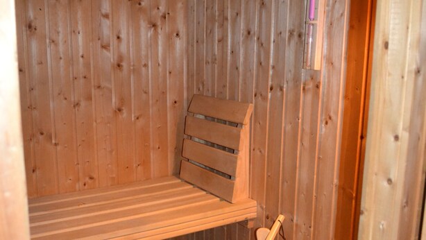 A wooden sauna with benches and a wooden bucket.