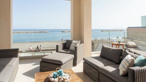 A balcony with wicker furniture, a wooden table with candles, and a view of the sea. - CELESTINE, beach front villa with roof top pool and spectacular views. (Kolymvari)