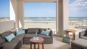 A balcony with a view of the beach, furnished with a sofa, two small tables, and decorative pillows. - CELESTINE, beach front villa with roof top pool and spectacular views. (Kolymvari)