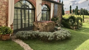 Een rustiek gebouw met grote boogvensters, een stenen waterpartij en een verzorgde tuin.
