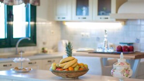 A kitchen with a fruit bowl on the counter, a decorative jar, and a window with curtains.