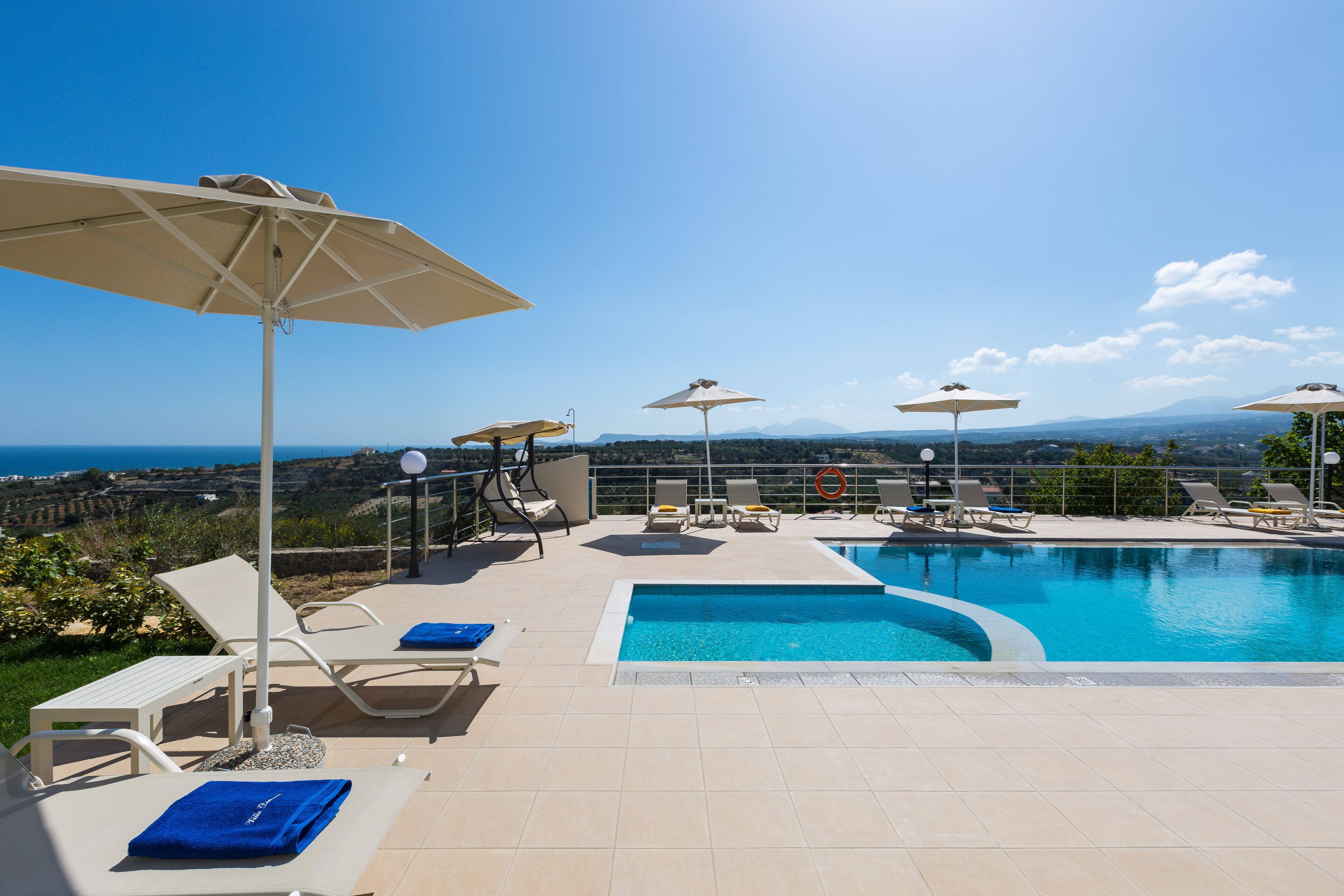 Ein Poolbereich auf dem Dach mit Liegestühlen und Sonnenschirmen mit Blick auf eine malerische Landschaft.