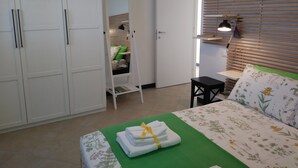 Een slaapkamer met een bed, een groen vloerkleed, een nachtkastje, een kledingkast en een spiegel.