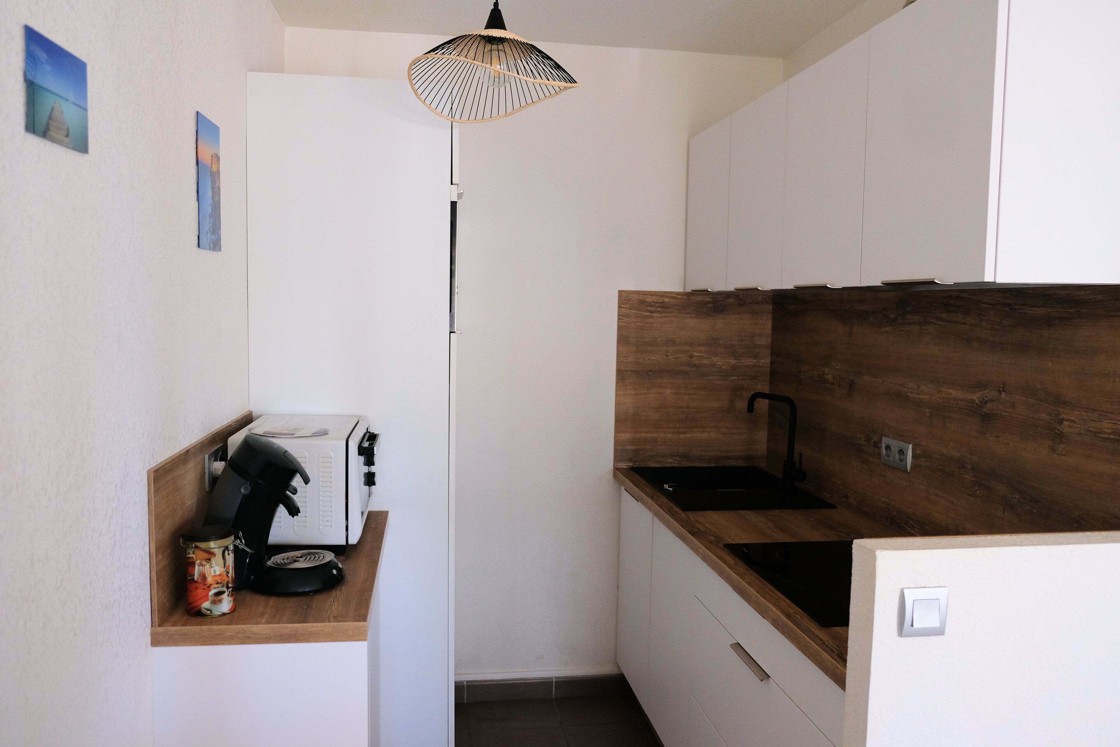 A compact kitchen with a wooden countertop, a built-in oven, and a coffee machine on a shelf.