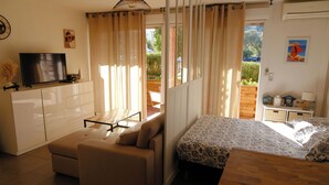 A room with a bed, a sofa, a television, and a window with curtains. - Studio - Porto Vecchio (Porto-Vecchio)