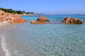 A beach with clear shallow waters, rocky outcrops, and a distant shoreline. - Studio - Porto Vecchio (Porto-Vecchio)