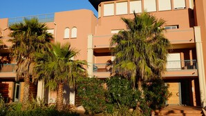 A multi-story building with balconies, palm trees, and a clear blue sky. - Studio - Porto Vecchio (Porto-Vecchio)
