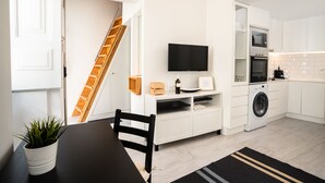 Eine moderne Küche mit weißen Schränken, einer integrierten Waschmaschine und einem Flachbildfernseher.