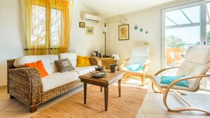 Una sala de estar con un sofá, una mesa de centro, una silla de mimbre y un sillón.