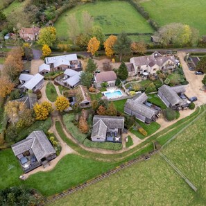 An aerial view of a residential area with multiple houses, a swimming pool, and well-maintained lawns.