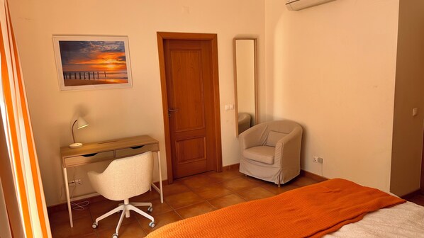 A bedroom with a bed, a desk with a chair, a door, and a painting on the wall. - PEACEFUL COZY COMFORTABLE SUNNY VILLA (PRAIA DO CARVOEIRO, LAGOA)