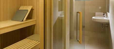A sauna with wooden benches and a glass door leading to a shower area with a sink and mirror.