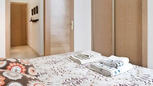 Une chambre à coucher avec un lit, une armoire en bois et une porte donnant sur une autre pièce.