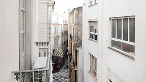 Une ruelle étroite entre deux bâtiments, avec une petite table et des plantes en pot sur le côté gauche.