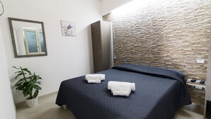 A hotel room with a bed, a wardrobe, a potted plant, and a textured wall. - B&B room with swimming pool (Gasponi)