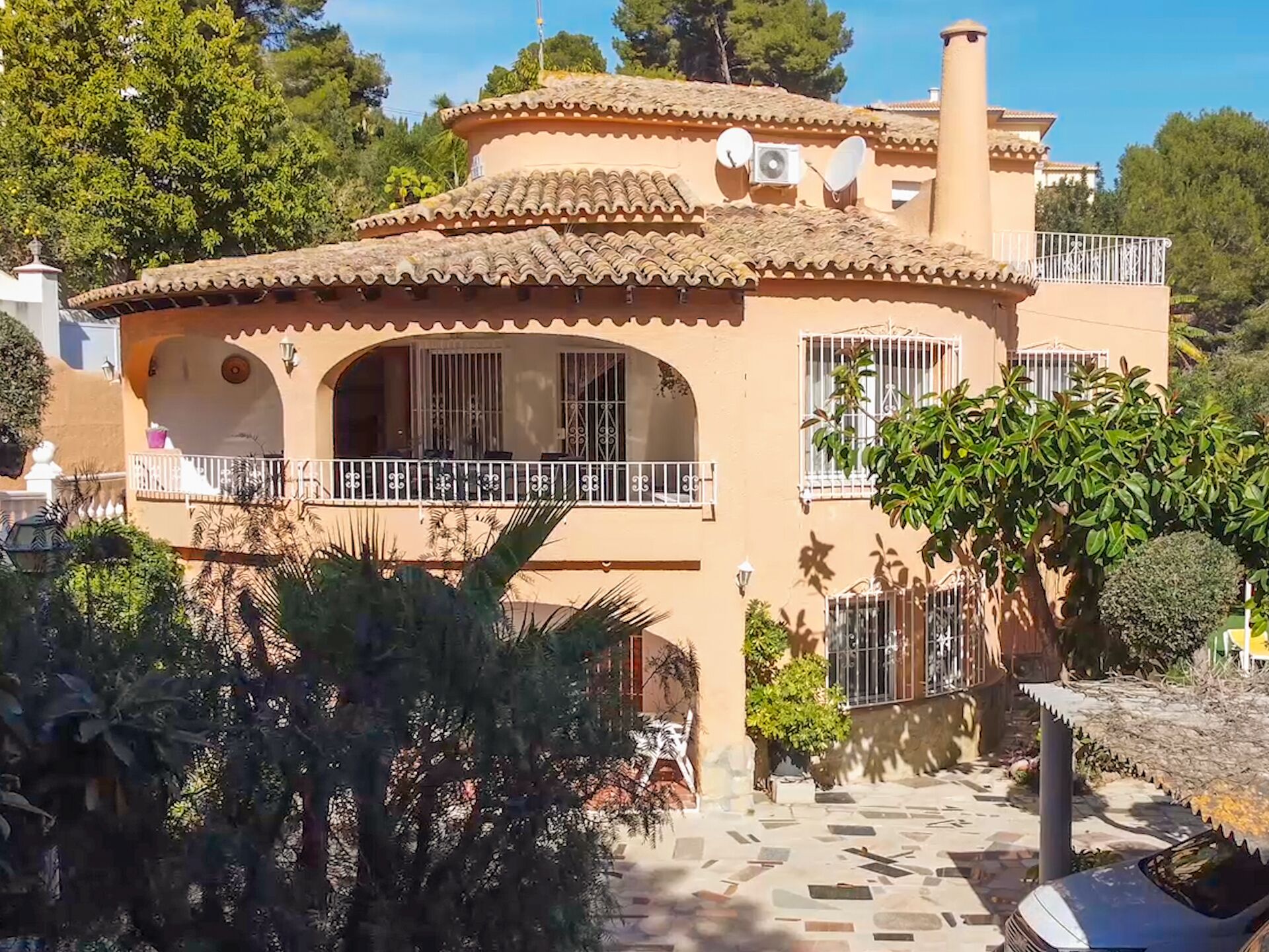 Un bâtiment de style méditerranéen, doté d’un toit en tuiles, d’antennes paraboliques et d’un balcon avec une balustrade blanche.