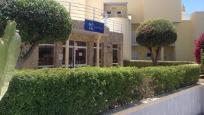 Un bâtiment à la façade en pierre, une enseigne bleue avec un logo en forme d’étoile et une antenne parabolique.
