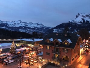A hotel with a cafe, outdoor seating, and a view of snow-covered mountains.