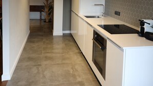 A modern kitchen with white cabinetry, a black countertop, and a hexagonal backsplash.