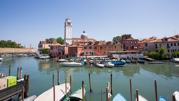 A canal with boats docked, historic buildings, and a prominent tower. - Venice Appartament Salini II (Venezia)