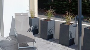 A modern outdoor seating area with a metal table and chairs, surrounded by planters with various plants. - Quiet apartment, close to shops, beaches, ferry terminal and thalasso spa  (Quiberon)
