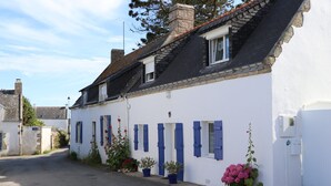 A white building with blue shutters, a sloped roof, and potted plants. - Quiet apartment, close to shops, beaches, ferry terminal and thalasso spa  (Quiberon)