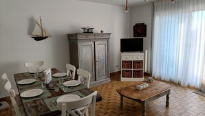 A dining area with a wooden table and chairs, a cabinet with baskets, and a television stand. - Quiet apartment, close to shops, beaches, ferry terminal and thalasso spa  (Quiberon)