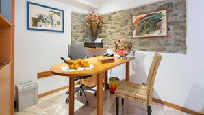 A dining area with a wooden table, chairs, and a stone wall.